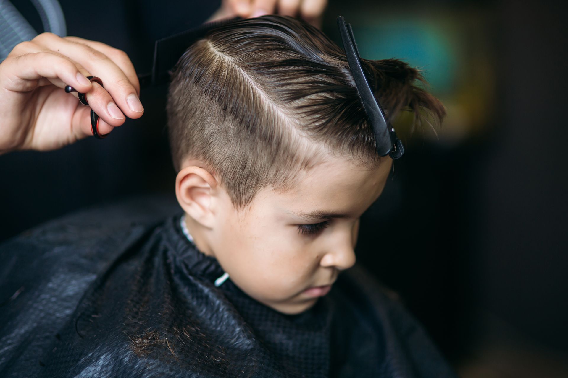 Person getting a side-part haircut at a barber shop