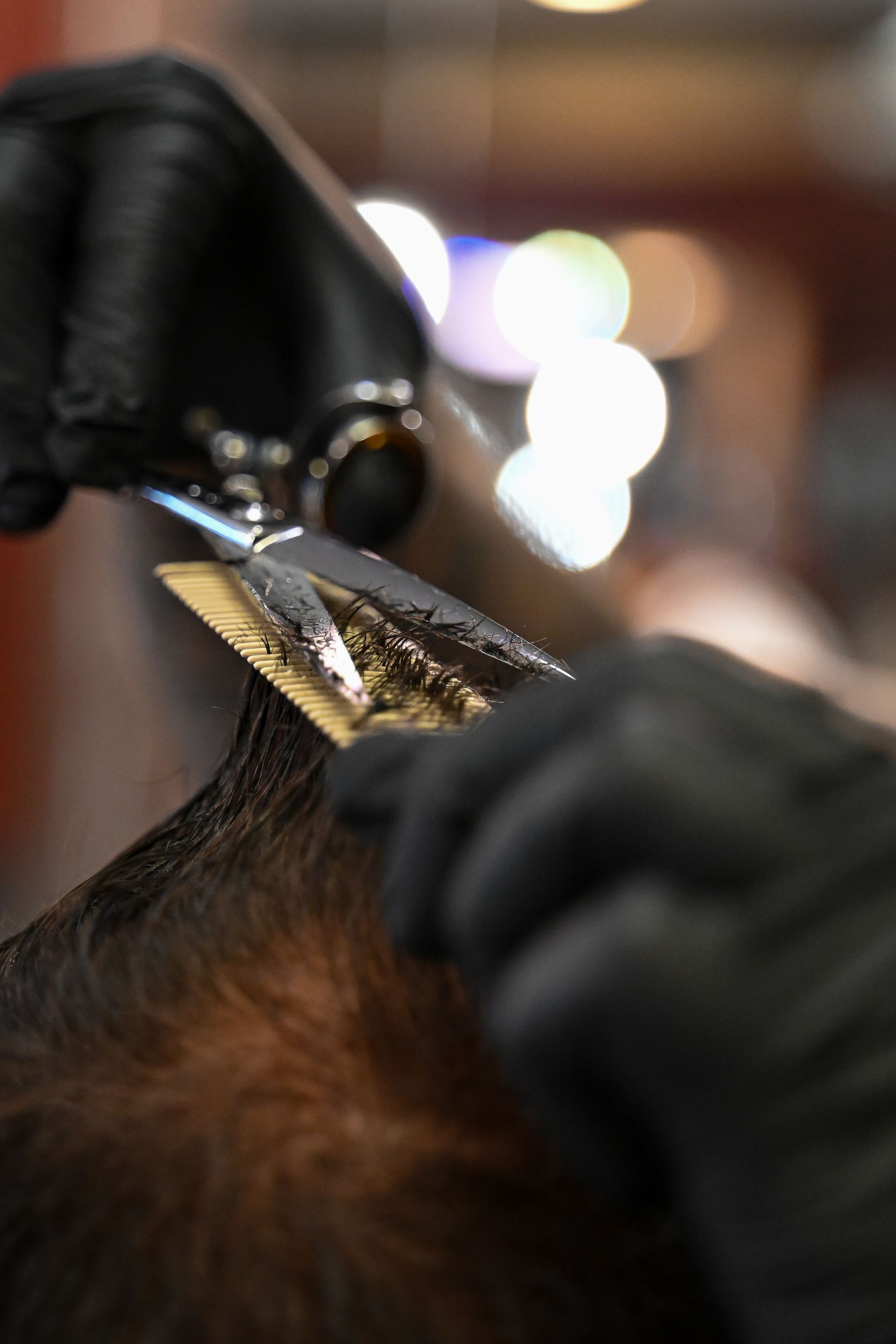 A close up of a person cutting their hair with scissors.