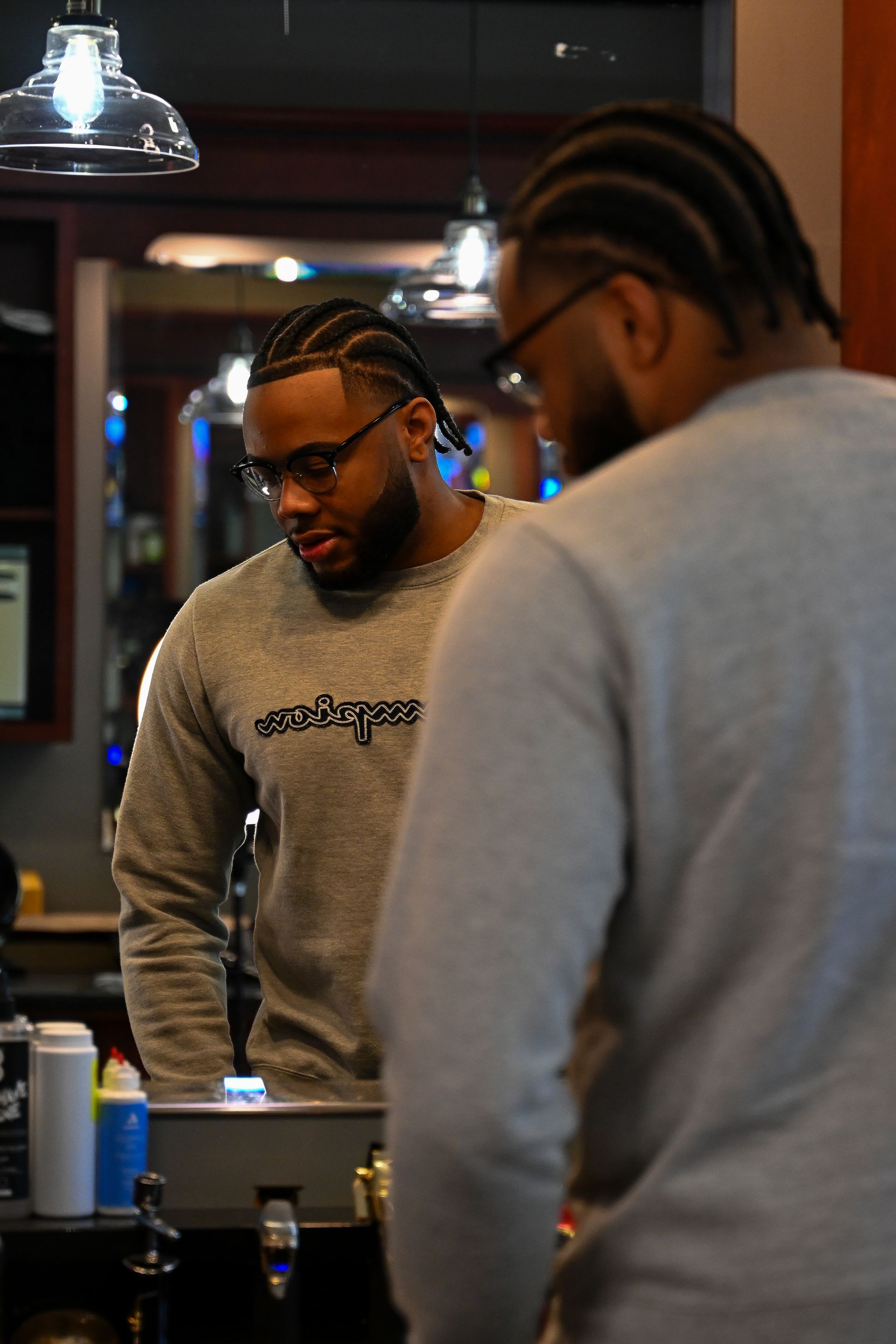 A man is looking at himself in the mirror in a barber shop.