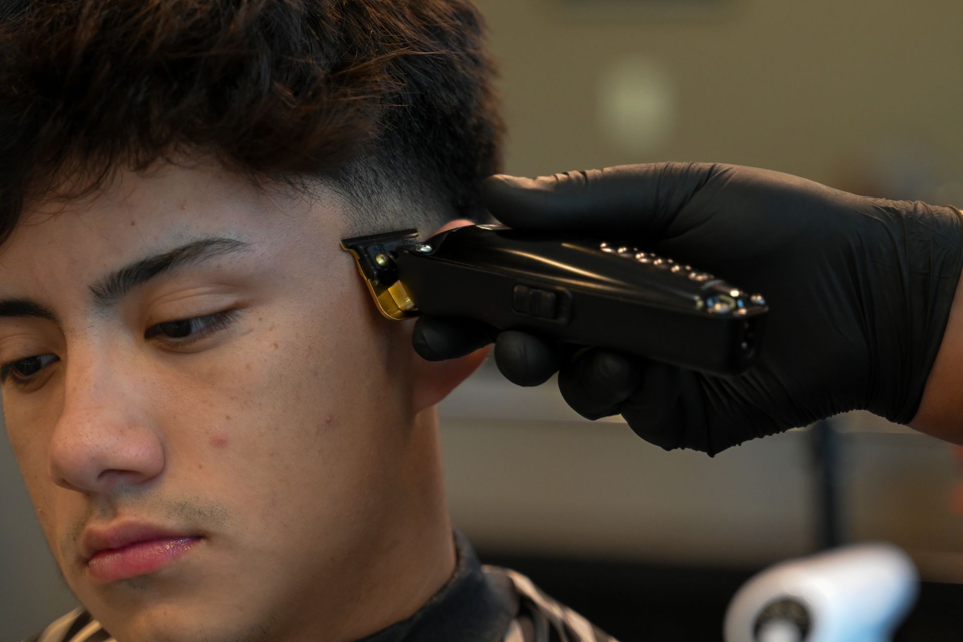 A man is getting his hair cut by a barber with a clipper.