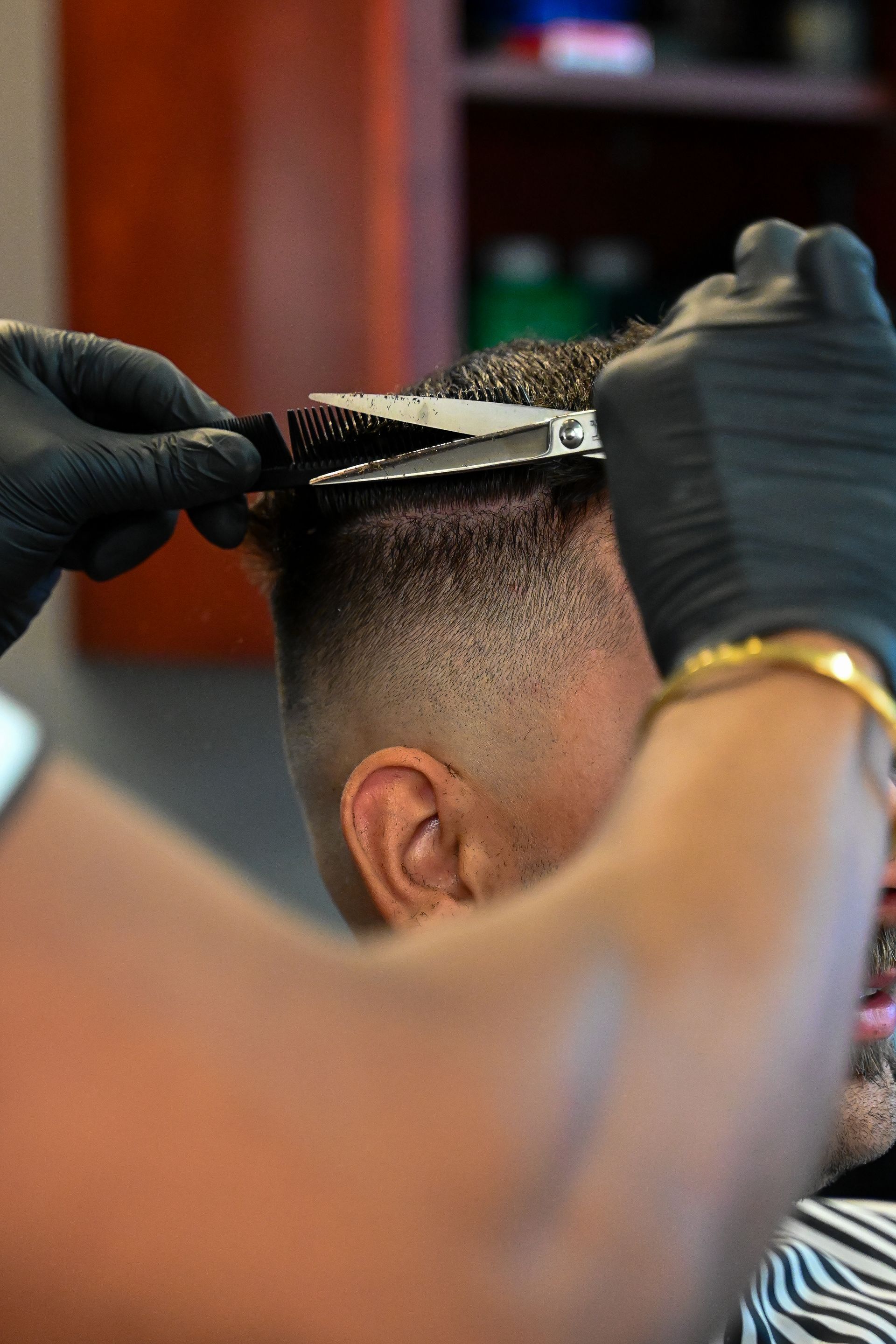 A man is getting his hair cut by a barber in a barber shop.