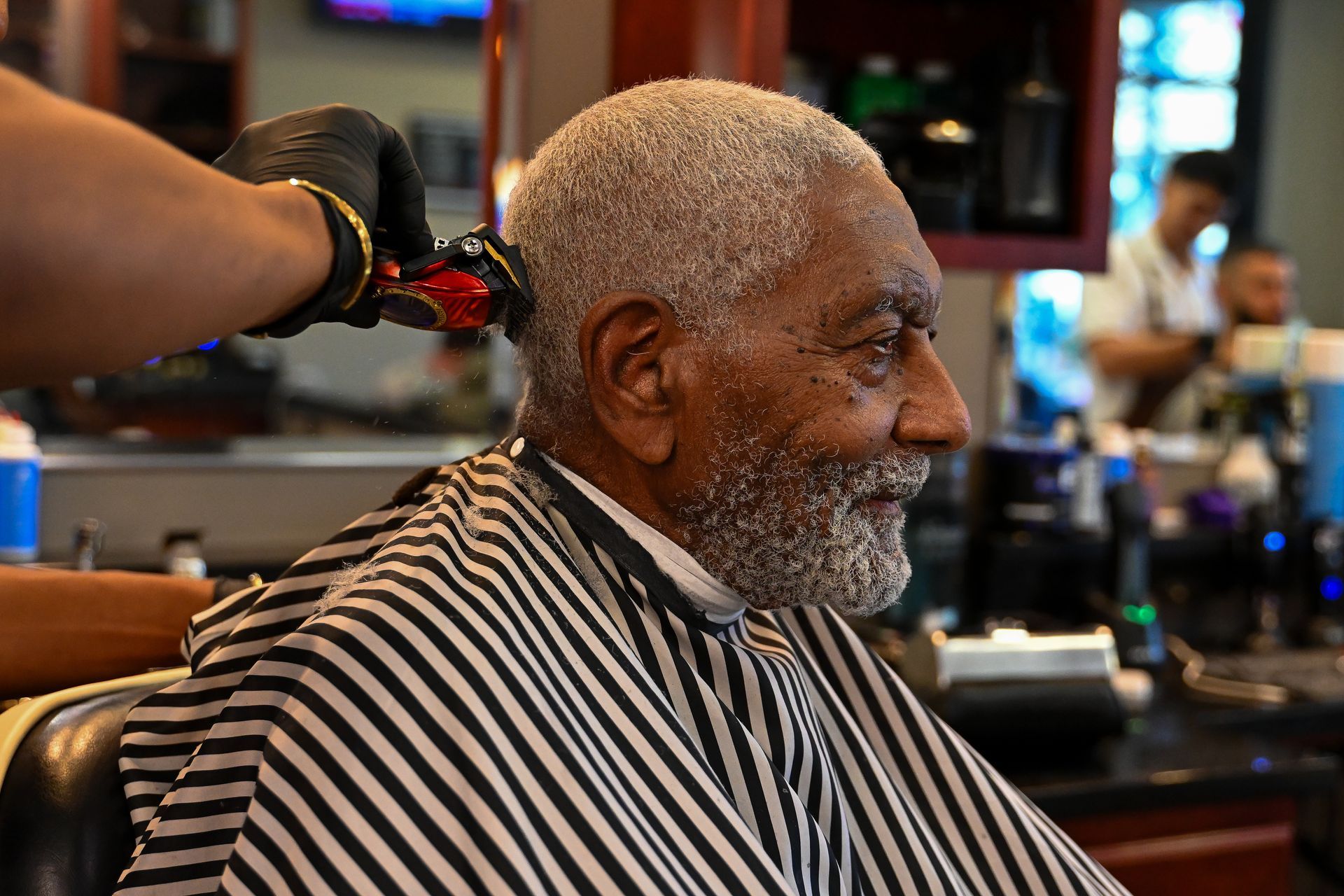 An older man is getting his hair cut at a barber shop.