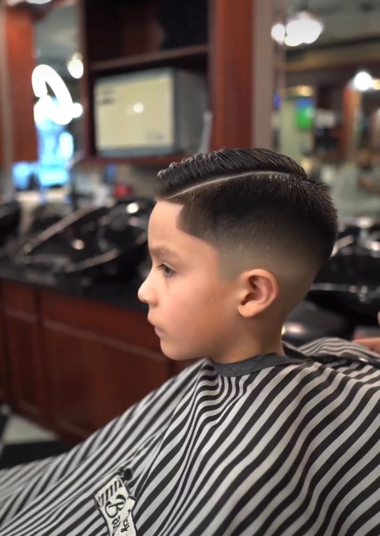 A young boy is getting his hair cut at a barber shop.
