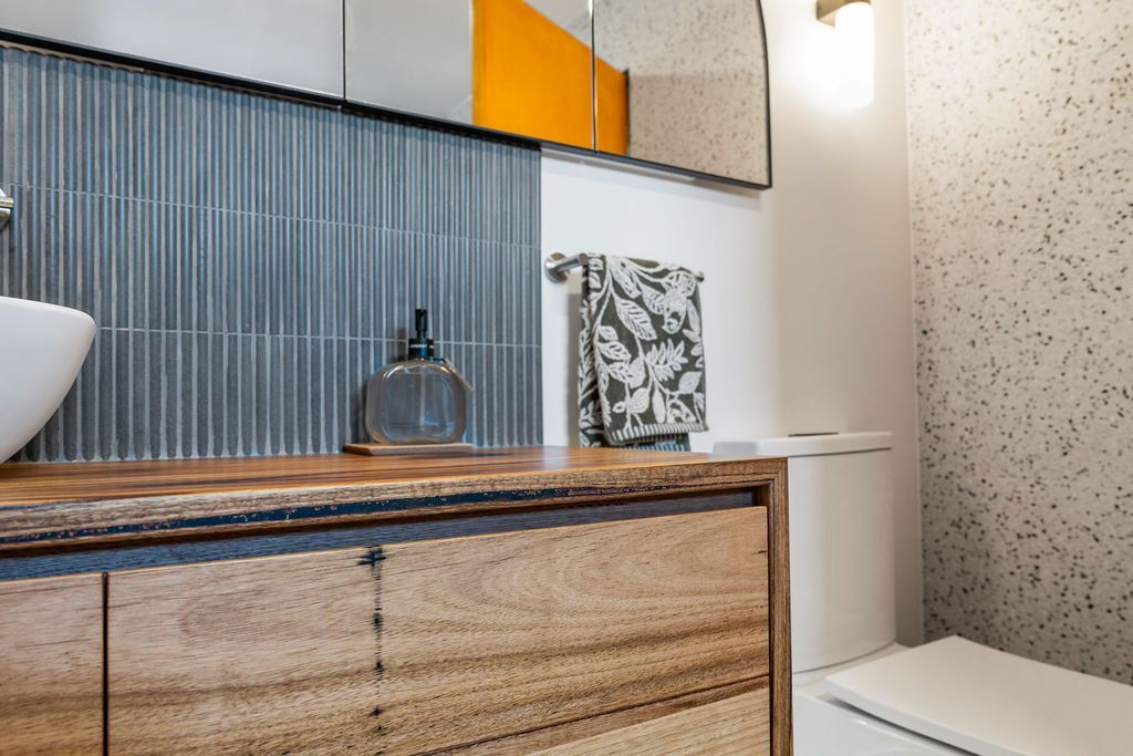 Modern bathroom vanity with wood cabinet, striped blue backsplash, and small decor items