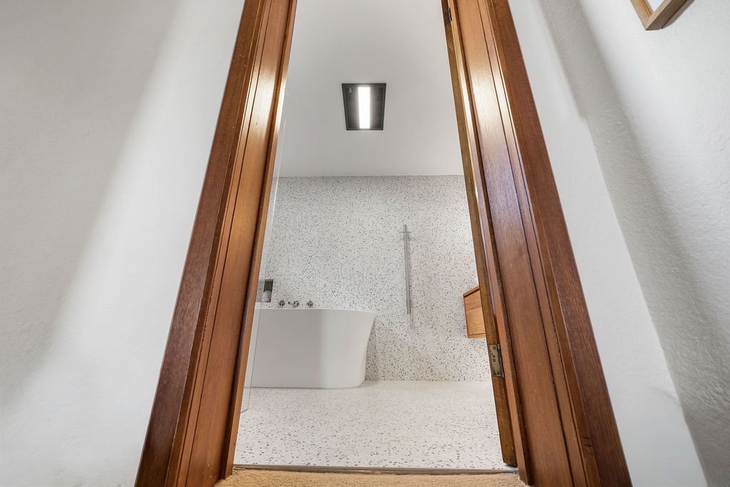 Stairwell with wooden handrails, white walls, and a ceiling light viewed from below
