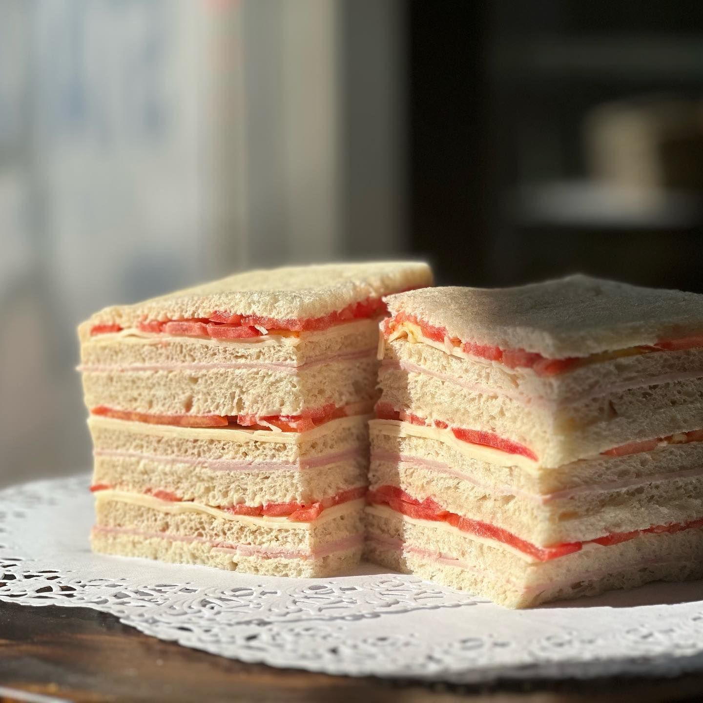 Two sandwiches are stacked on top of each other on a napkin on a table.