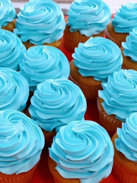A bunch of cupcakes with blue frosting on them