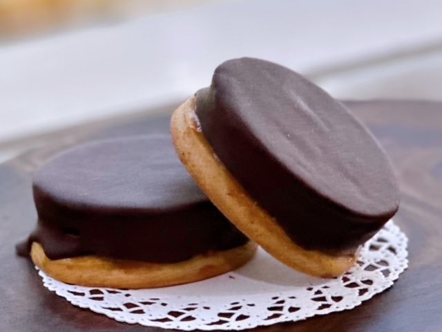 Two chocolate covered cookies on a white lace napkin