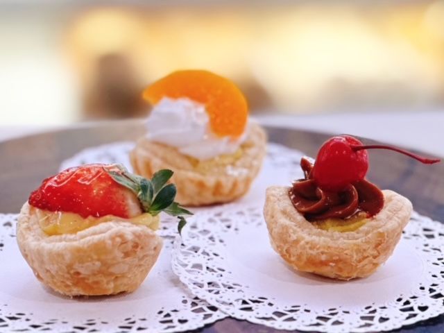 Three cupcakes with strawberries and a cherry on top