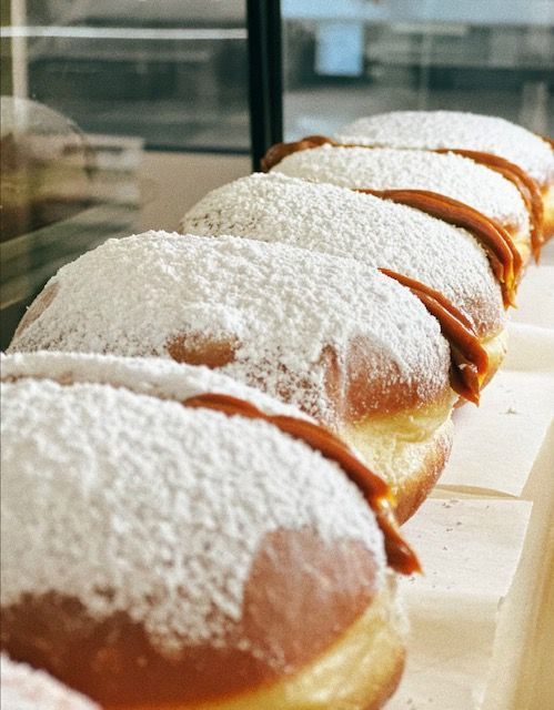 A row of donuts with powdered sugar on them