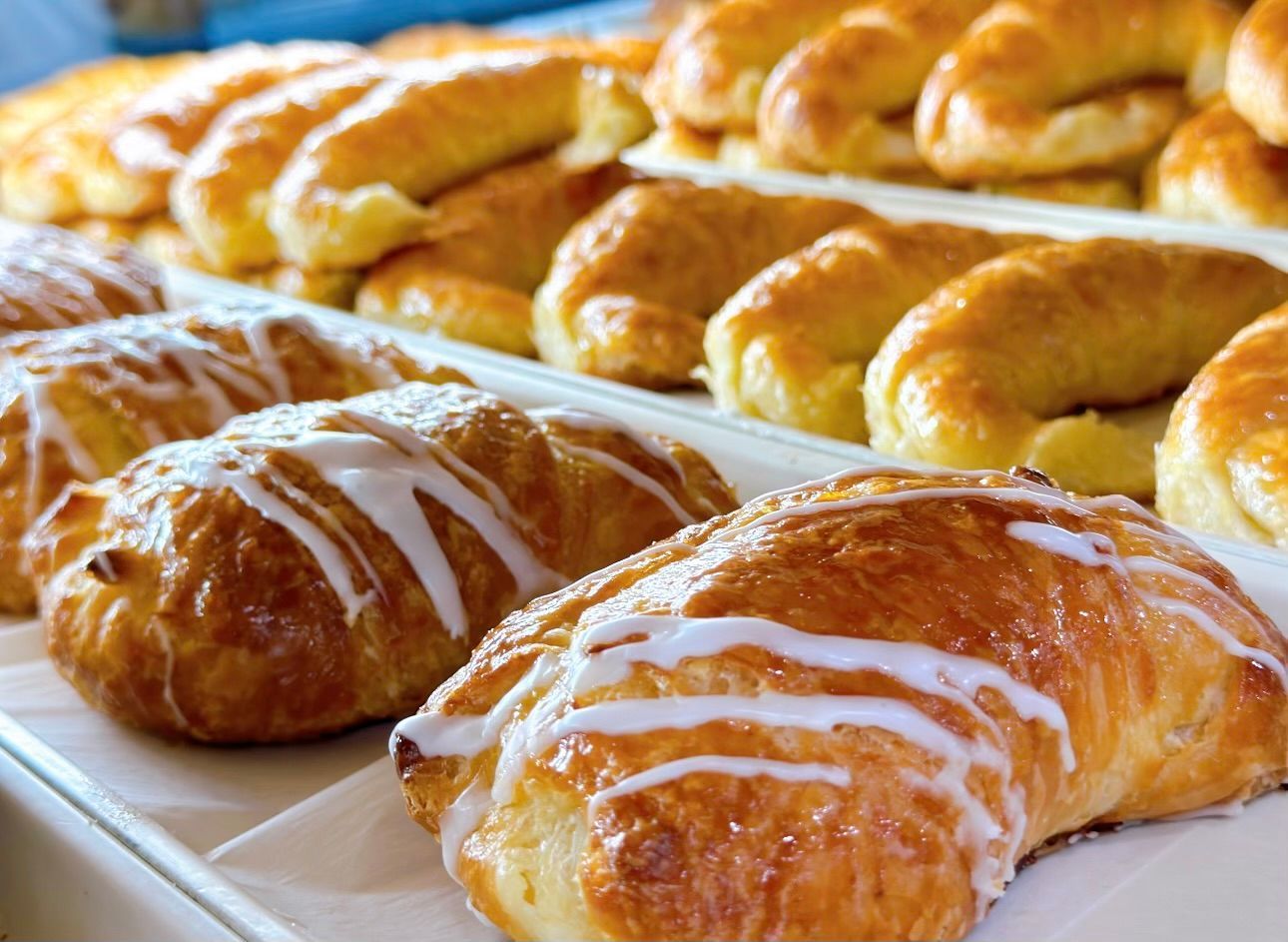 A tray of croissants with icing on them