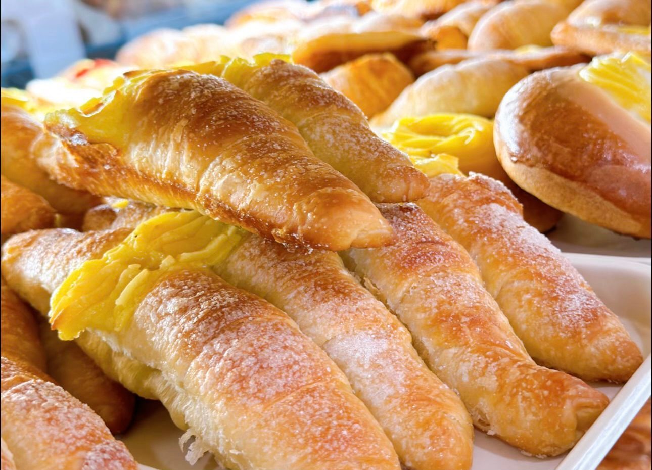 A bunch of croissants with yellow frosting on them