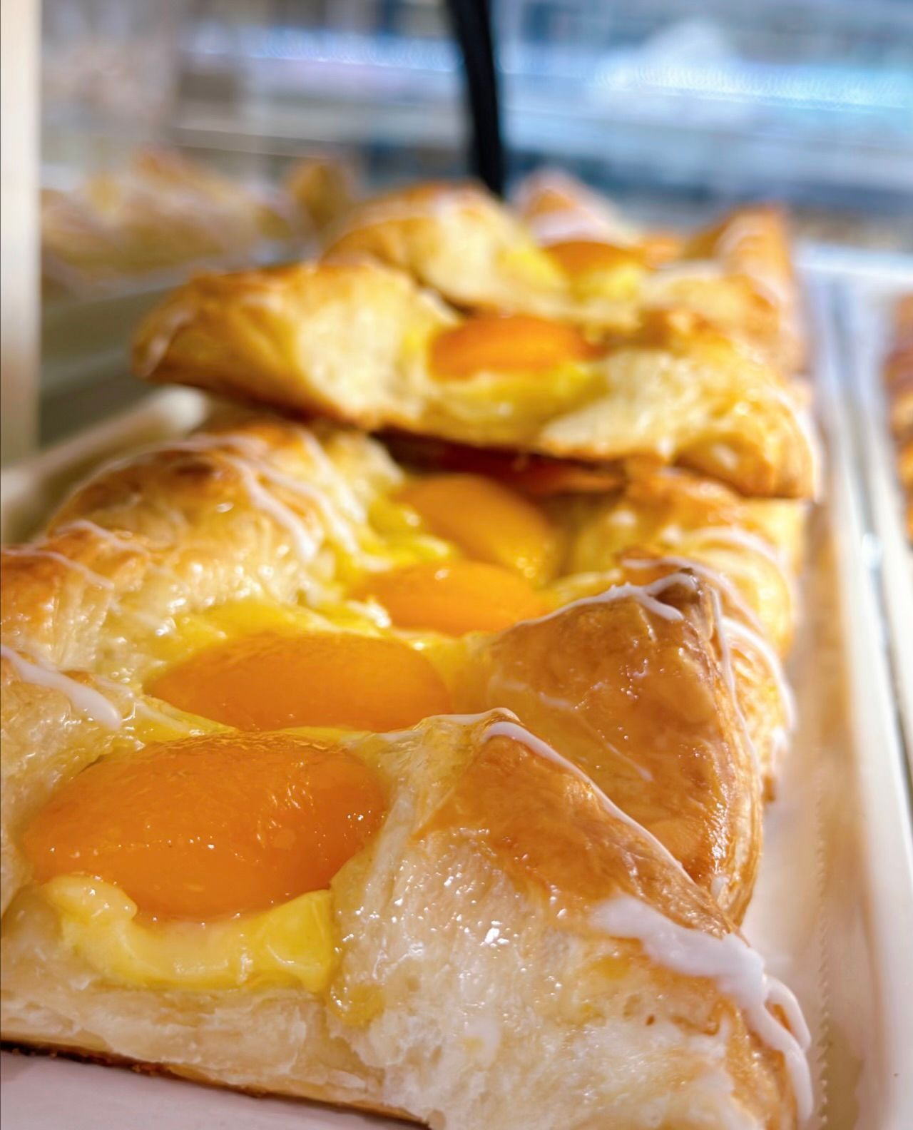 A close up of a peach danish pastry on a tray.