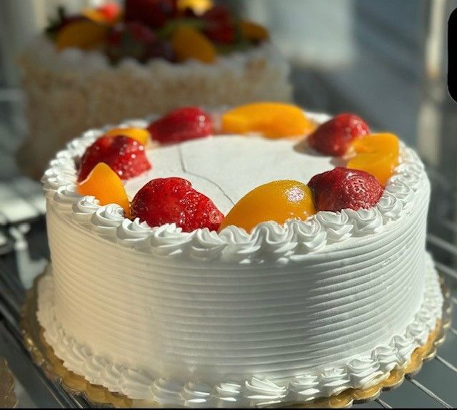 A white cake with strawberries and peaches on top