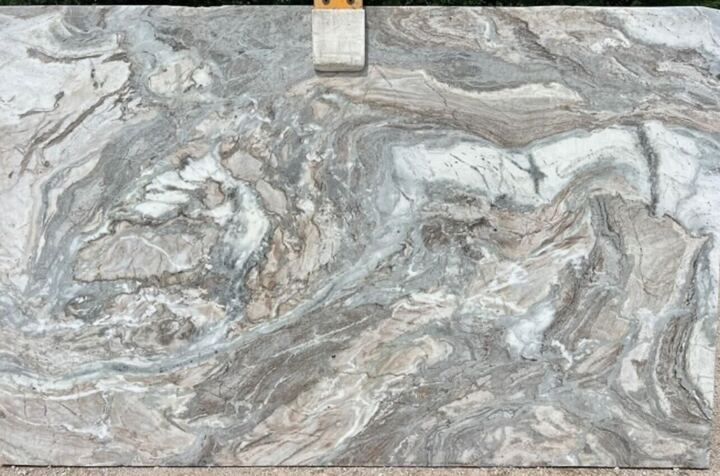 A marble slab with a swirl pattern is sitting on the ground.