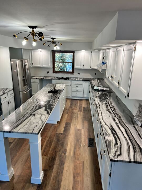 A kitchen with gray cabinets and marble counter tops.