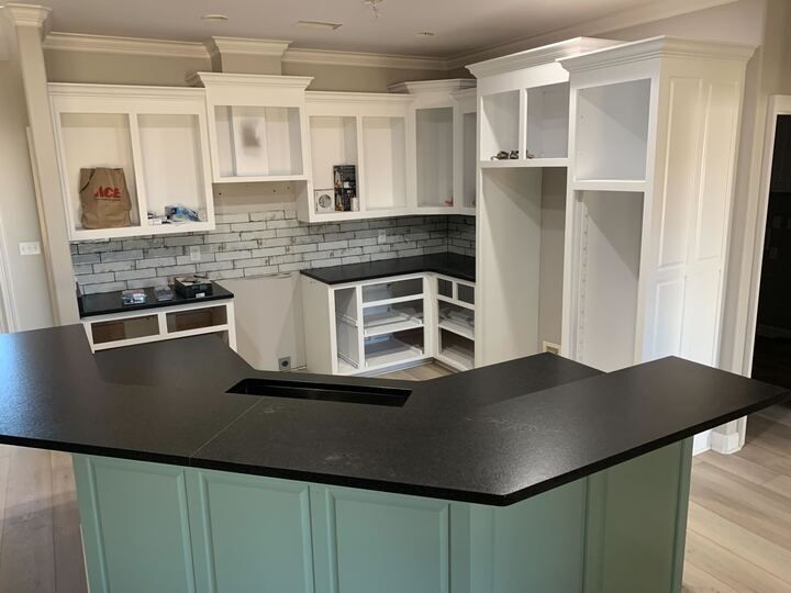 A kitchen with a black counter top and white cabinets.