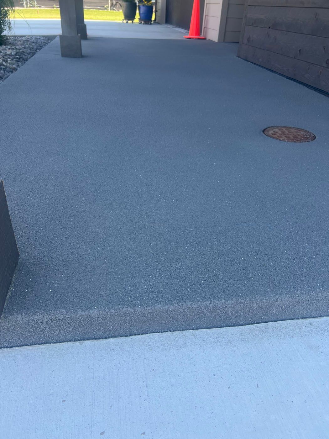 A concrete entryway with a gray, textured surface and a single step leading up to a house.