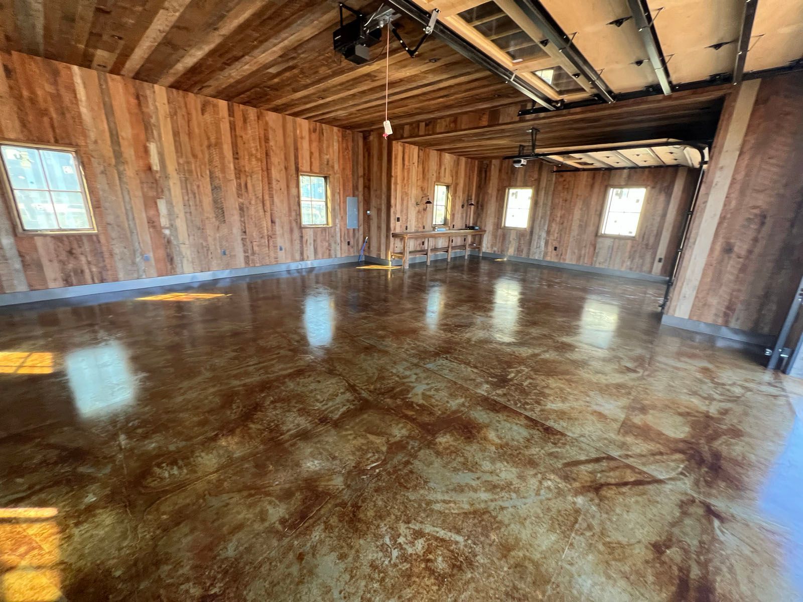 An interior view of a garage with wood-paneled walls and a high-gloss, marbled-finish concrete floor.