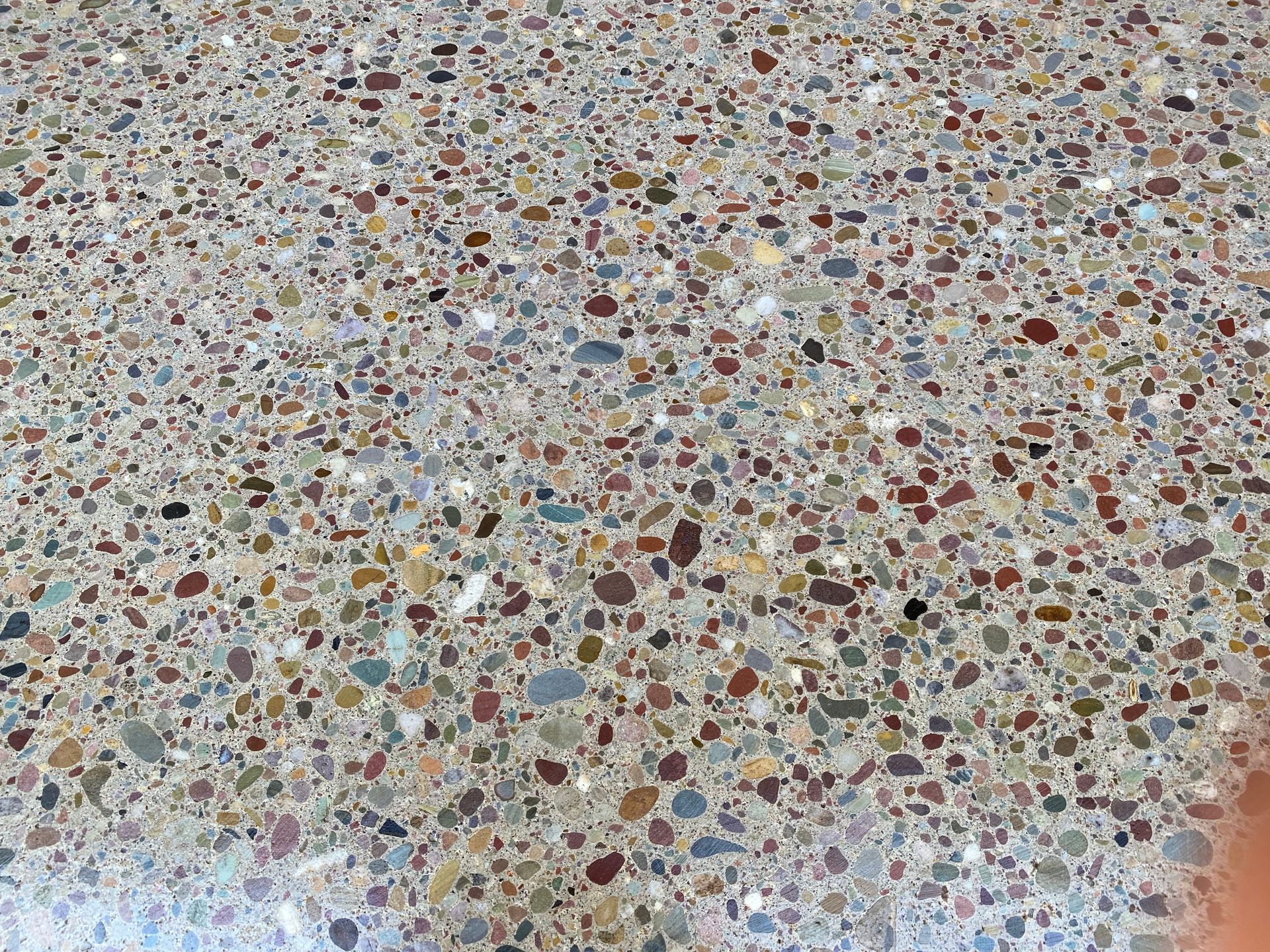 Polished concrete flooring featuring a dense mix of multi-colored aggregate stones in shades of grey, tan, and red.