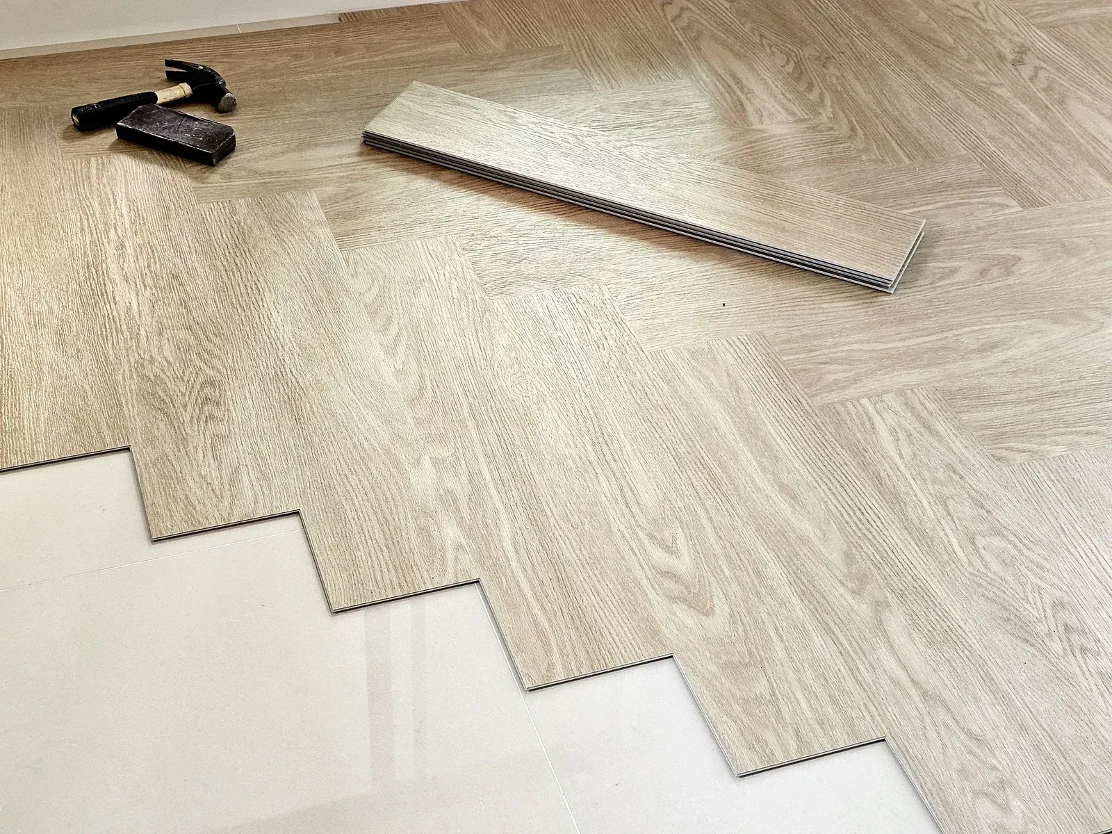 Laminate flooring planks and a flooring tool on a light wood floor during installation