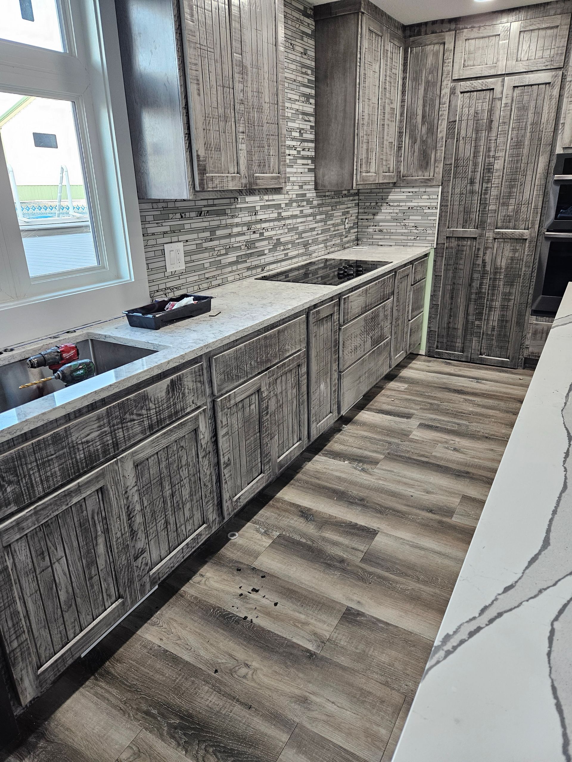 Bright white kitchen with stainless steel stove, pale green cabinets, and a marble-pattern island table