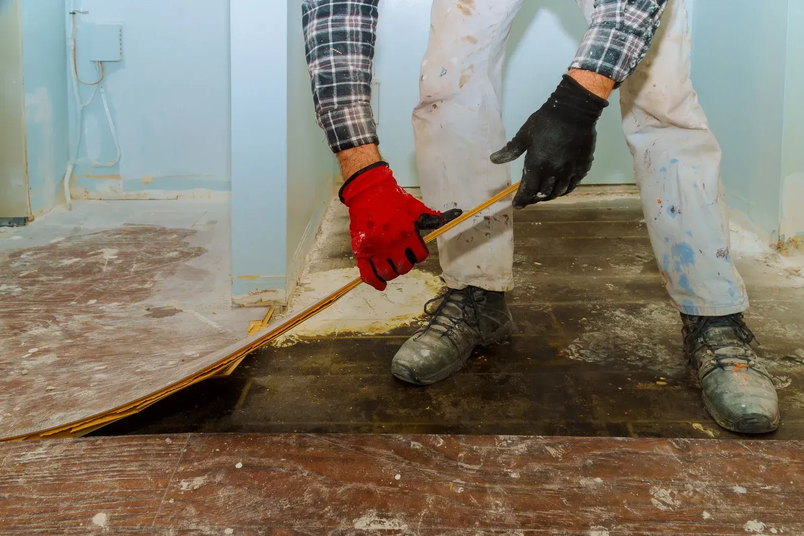 Damaged bathroom with exposed walls, debris on the floor, and a bathtub beside a wooden door