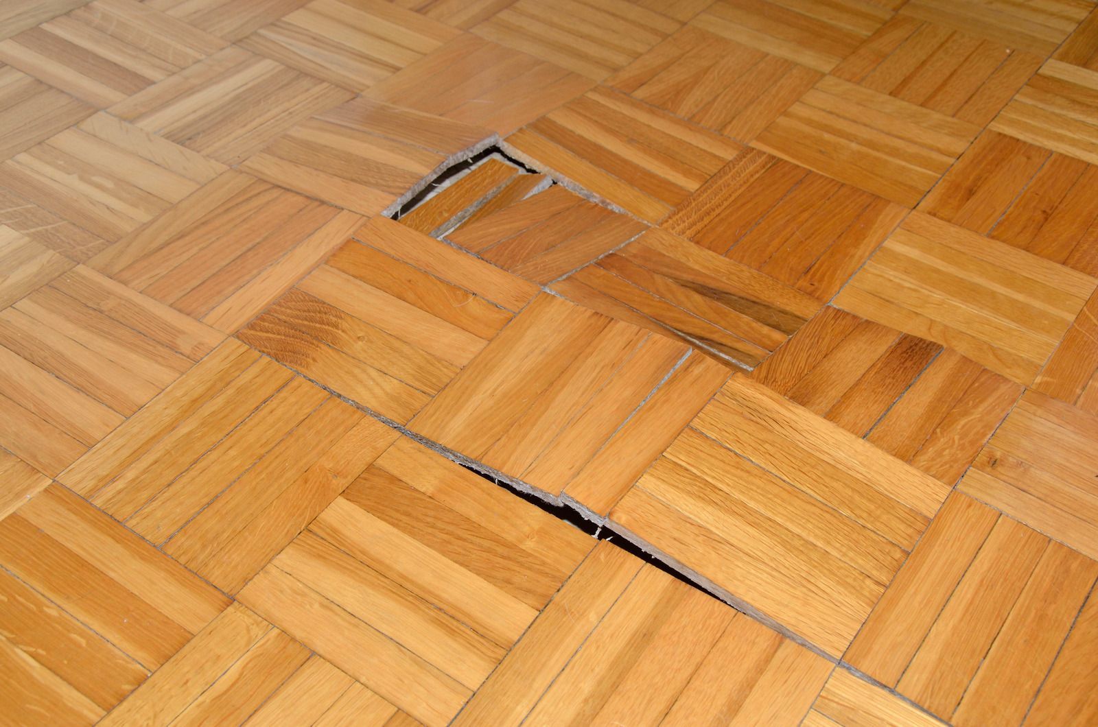Worker smoothing wet beige floor coating with a trowel in a room under renovation