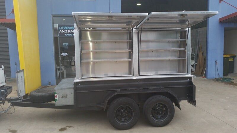 A Black Utility Trailer With Two Raised Aluminum Storage — Litzow’s Welding & Fabrication in Dundowran, QLD