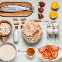 Baking ingredients on a wooden table: flour, bread, eggs, fish, shrimp, strawberries, and oranges
