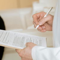 Gloved hands preparing a syringe injection into an arm in a clinical setting