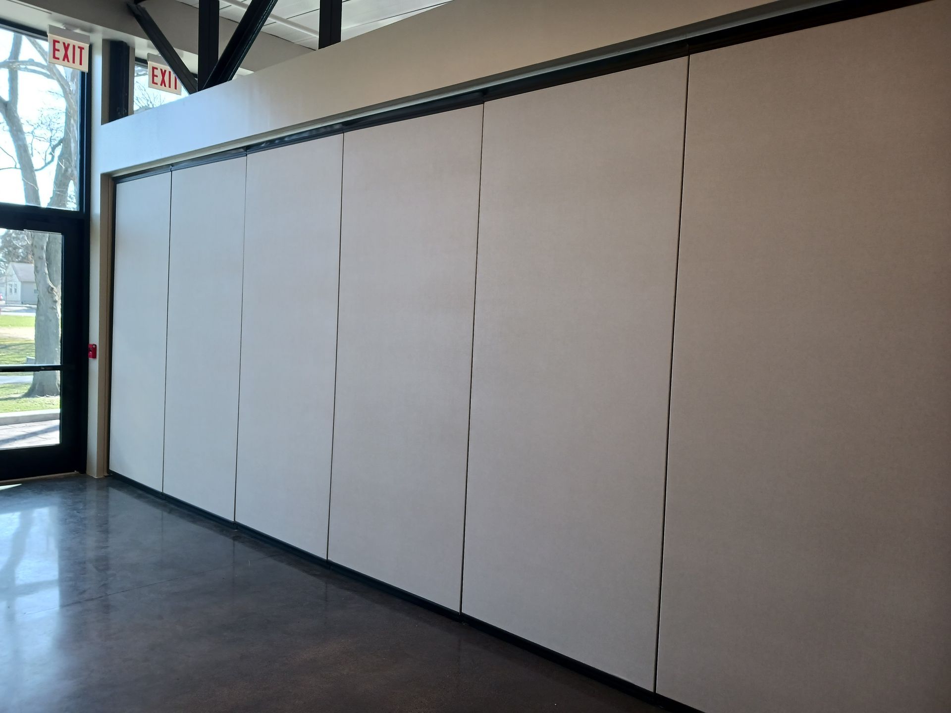A large room with a lot of glass doors and tables and chairs.