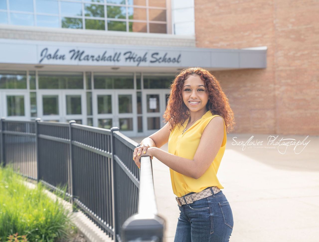 A woman is leaning on a railing in front of a high school.