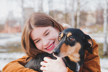 A woman is hugging a black and brown dog.