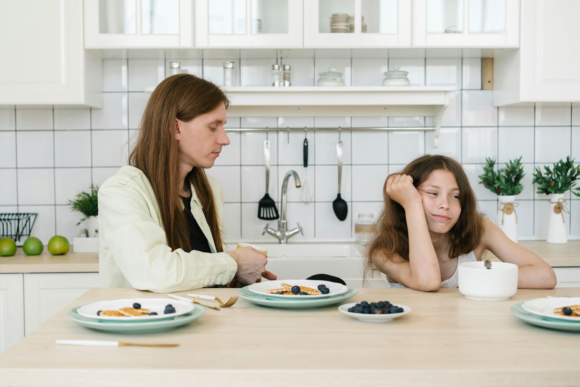 A woman and a girl are sitting at a table with plates of food.