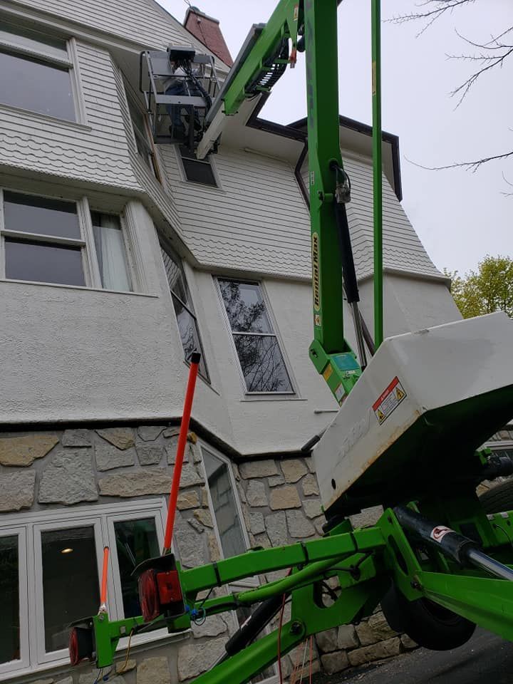Green lift near a white house with a stone facade, possibly for maintenance.