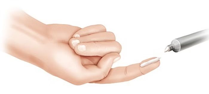 Eine Hand feilt sich mit einer Nagelfeile einen Fingernagel, Nahaufnahme vor hellem Hintergrund.