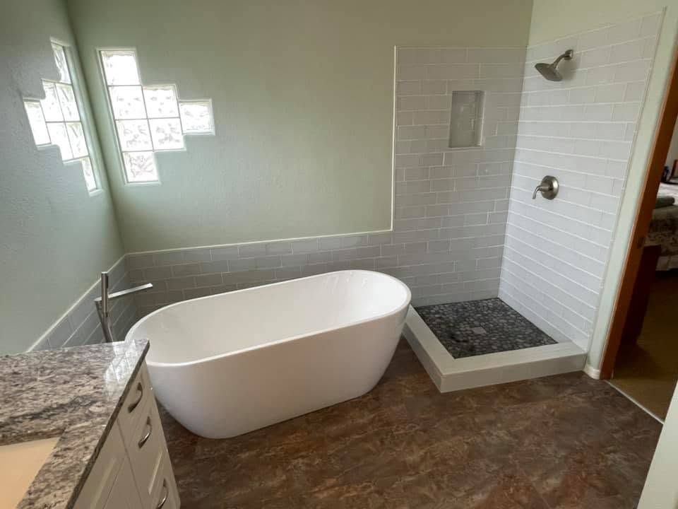 Modern bathroom with a freestanding tub, walk-in shower, and granite vanity countertop