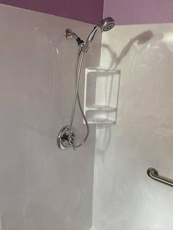 Shower caddy with a clear soap holder mounted on a white and purple bathroom wall