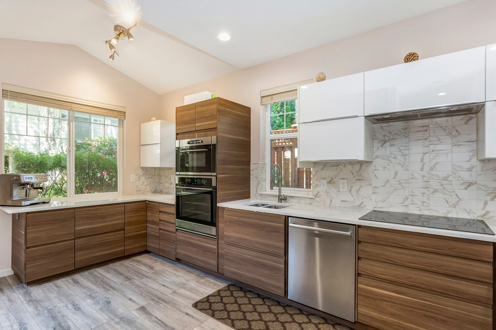 Modern kitchen with white cabinets, wood lower cabinets, marble backsplash, and stainless steel appliances