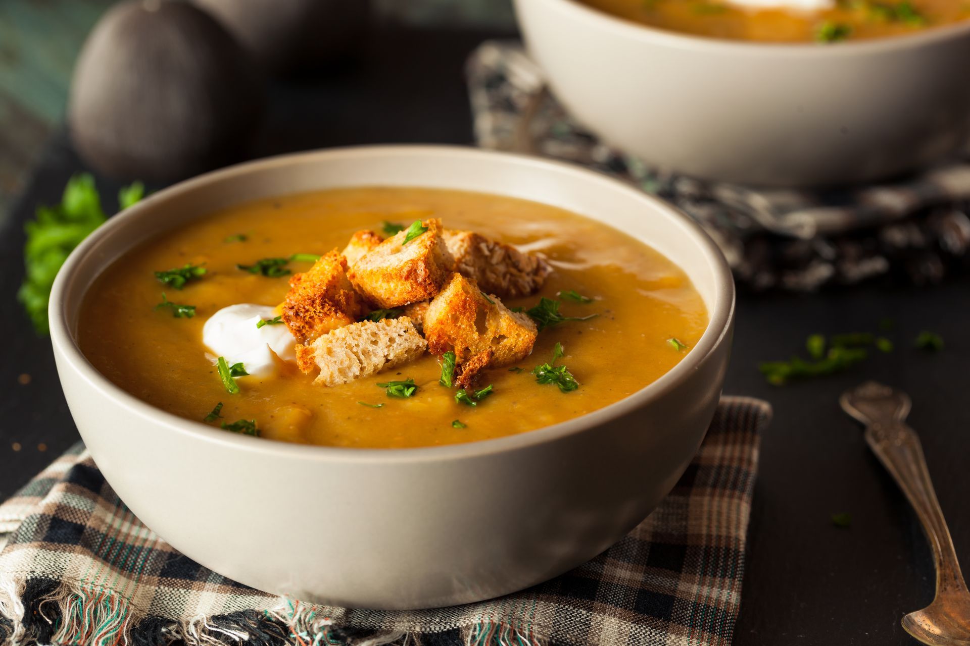 A bowl of soup with croutons and sour cream on top.