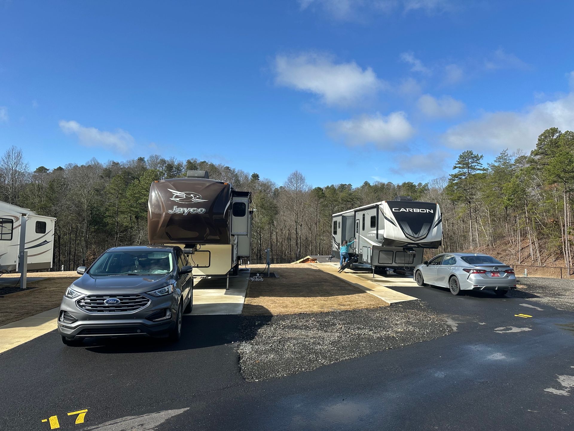 A rv with an awning is parked in the middle of a forest.