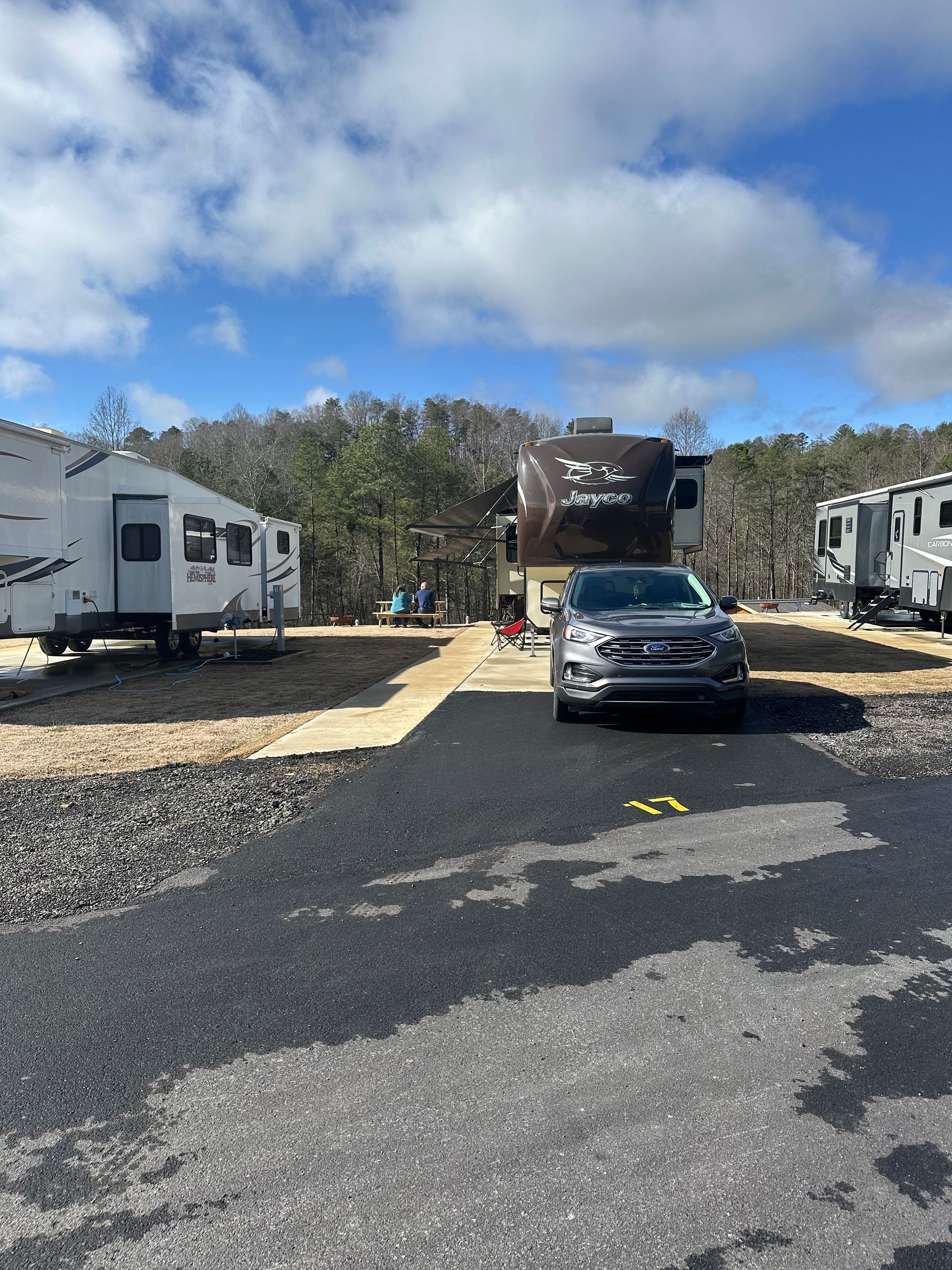 A row of rvs are parked on the side of a dirt road.