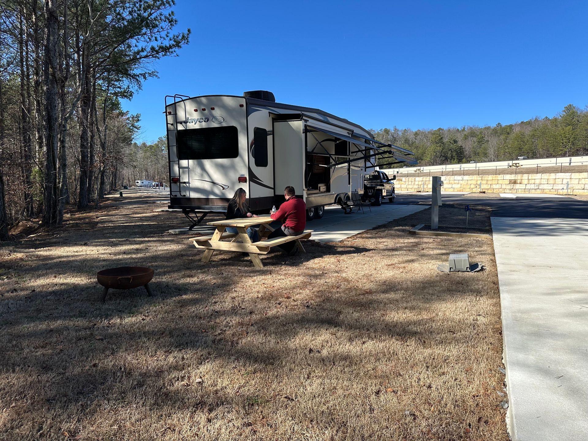 A rv with an awning is parked in the middle of a forest.