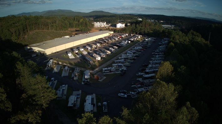 A row of rvs are parked on the side of a dirt road.