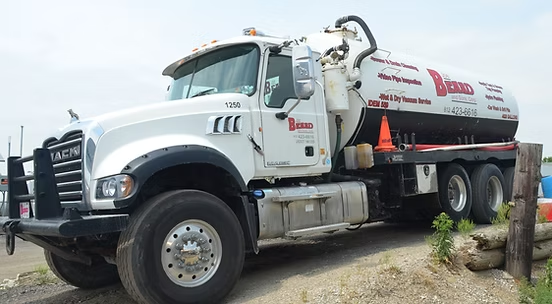 A white vacuum truck is parked on the side of the road.