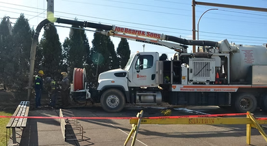 A vacuum truck is parked on the side of the road.