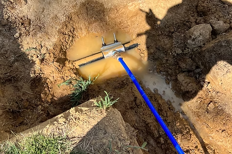A blue hose is sticking out of a hole in the ground.