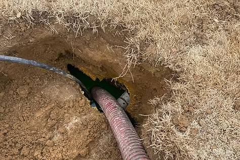 A hose is coming out of a hole in the ground.