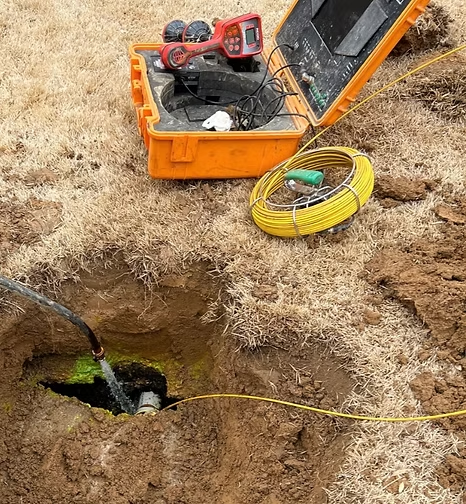 A hose is coming out of a hole in the ground next to a camera.